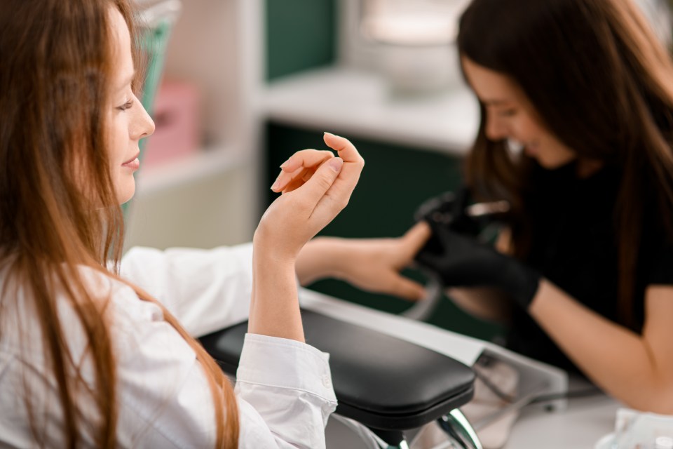 Woman admiring her freshly manicured hand at a nail salon.