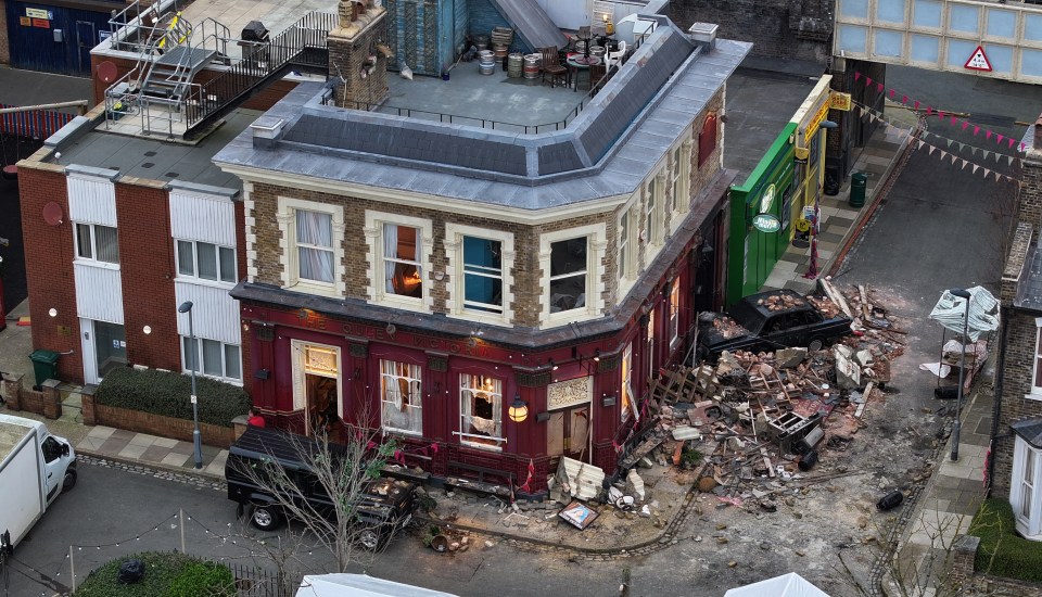 Aerial view of the Queen Victoria pub after an explosion, showing significant damage and a car crashed into the building.