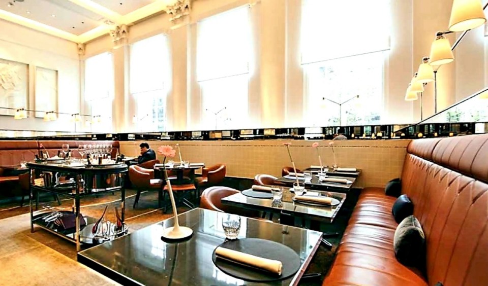 Interior view of a restaurant with leather banquettes and small tables.