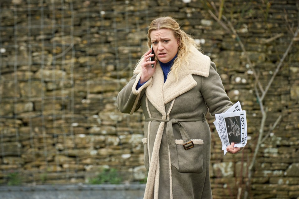 Woman on phone holding lost cat poster.