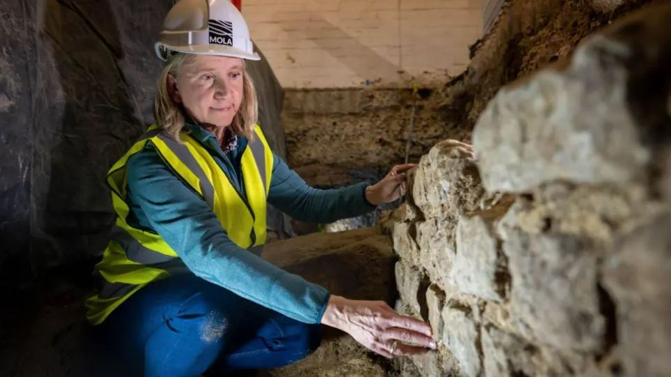 Archaeologist examining a 2000-year-old stone wall.