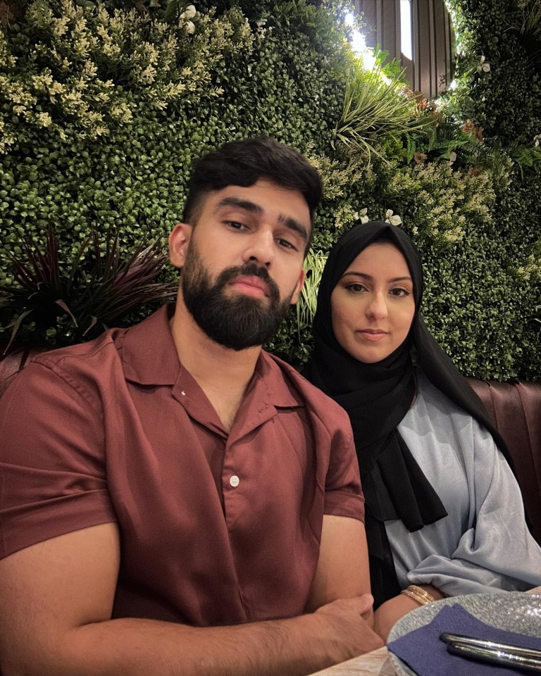 Couple posing together in front of a green wall.