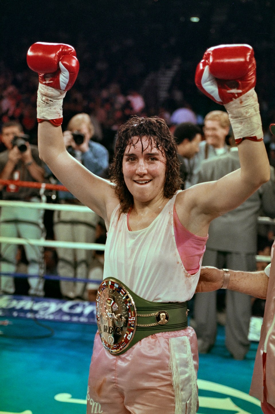 Christy Martin victorious in a WBC Championship Boxing Lightweight fight, raising her arms in celebration.