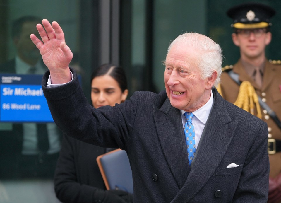 King Charles III waves to students and the public.