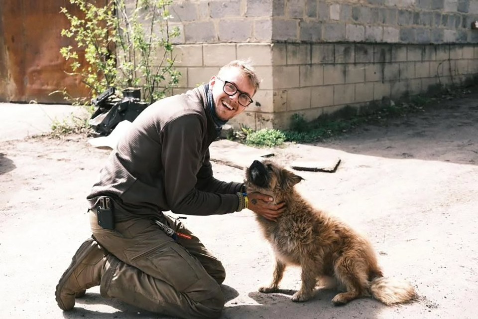 British humanitarian worker Edward Scott kneeling and petting a dog in Ukraine.