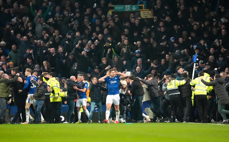 Everton's James Tarkowski celebrates a goal as fans rush the pitch.