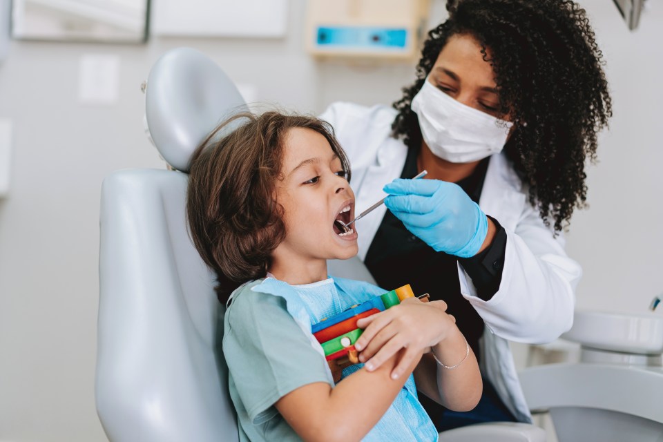 A dentist examining a young child's teeth.