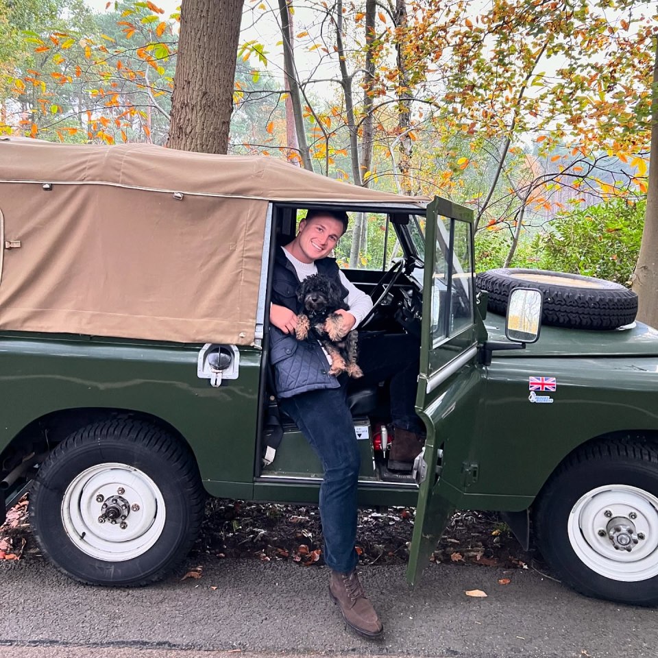 Man sitting in a Land Rover with his dog.