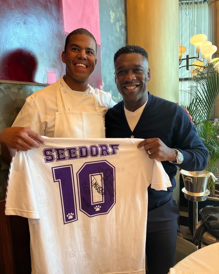 Clarence Seedorf and a chef holding a signed soccer jersey.