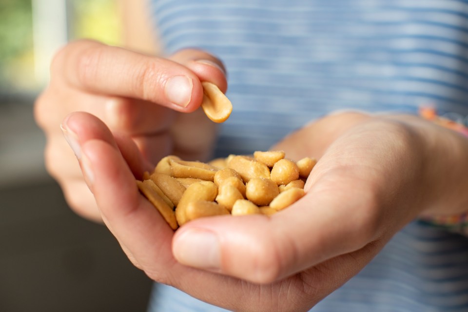 Close-up of a teenager's hands holding and eating salted peanuts.