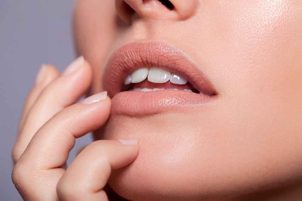 Close-up of a young woman's face, hand touching her chin.