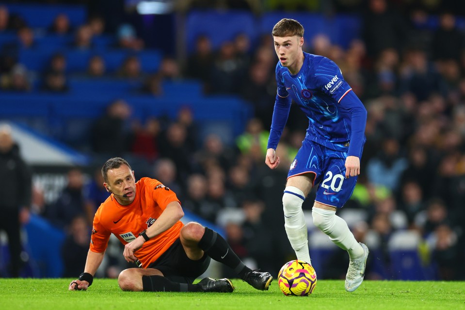 Cole Palmer of Chelsea dribbling past a referee.