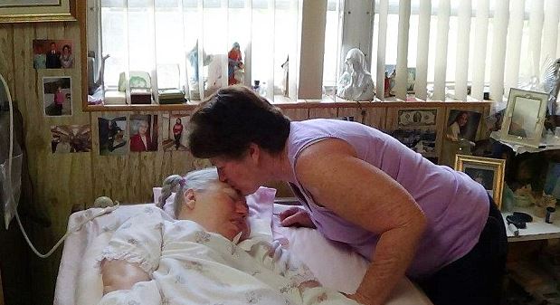 Woman kissing a woman lying in bed.