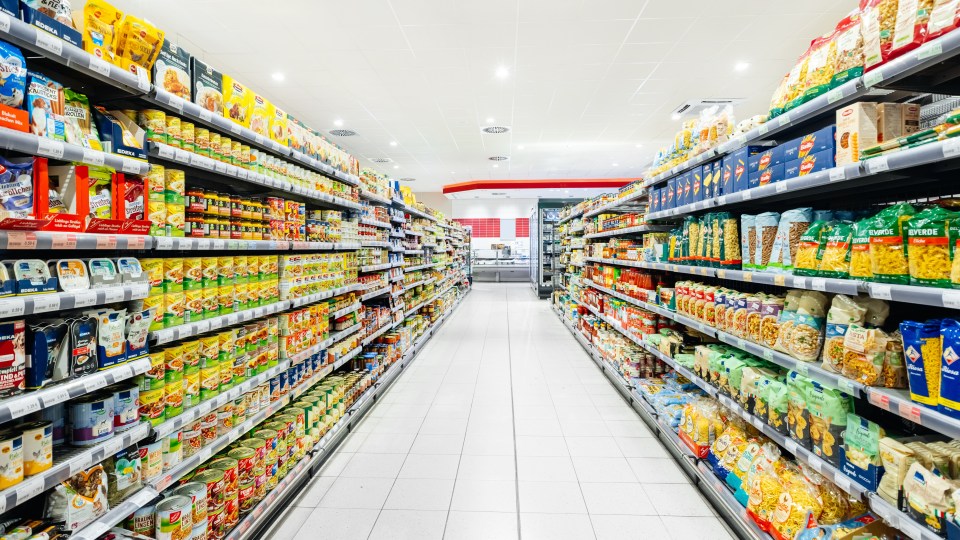 Supermarket aisle with shelves stocked with various food items.