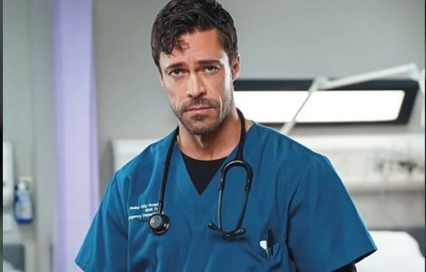 Olly in a hospital scrubs, portraying Flynn Byron in Casualty.