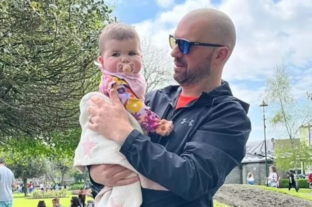 Man holding a baby in a park.