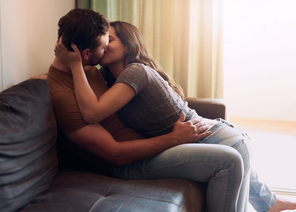 A young couple kissing on a sofa.