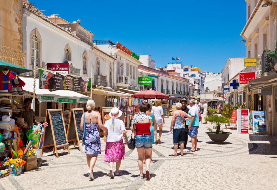 Tourists walking down a sunny street in Albufeira, Portugal.