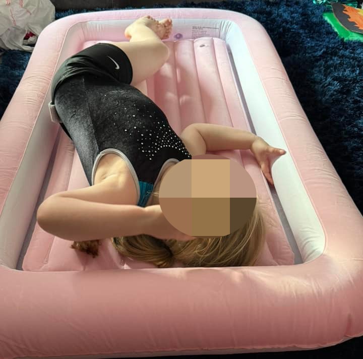 Child lying on a pink inflatable mattress.