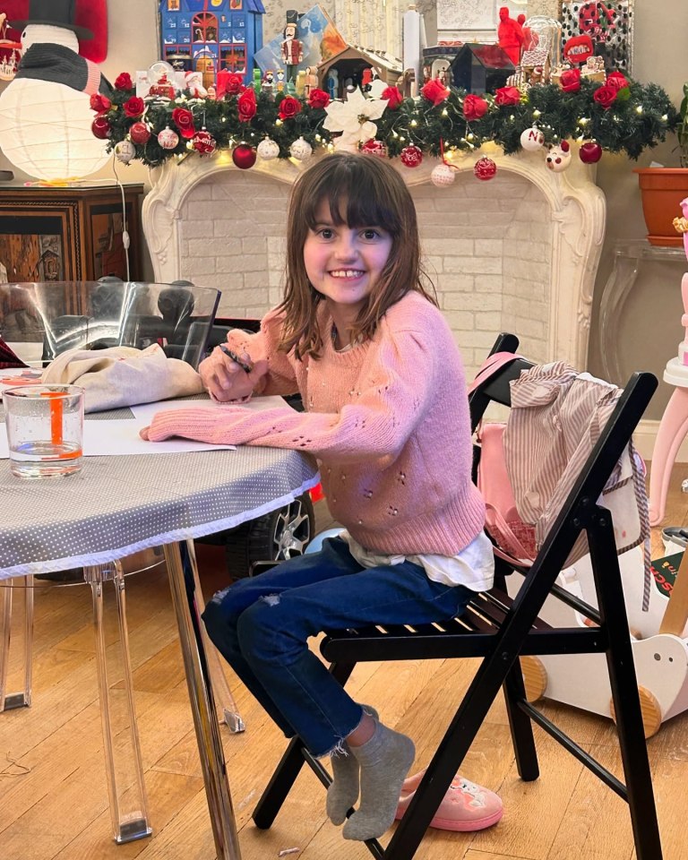 Girl with rare genetic disorder drawing at a table.