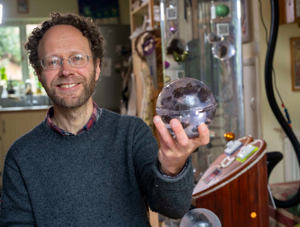 Man holding a glass sphere containing human feces.