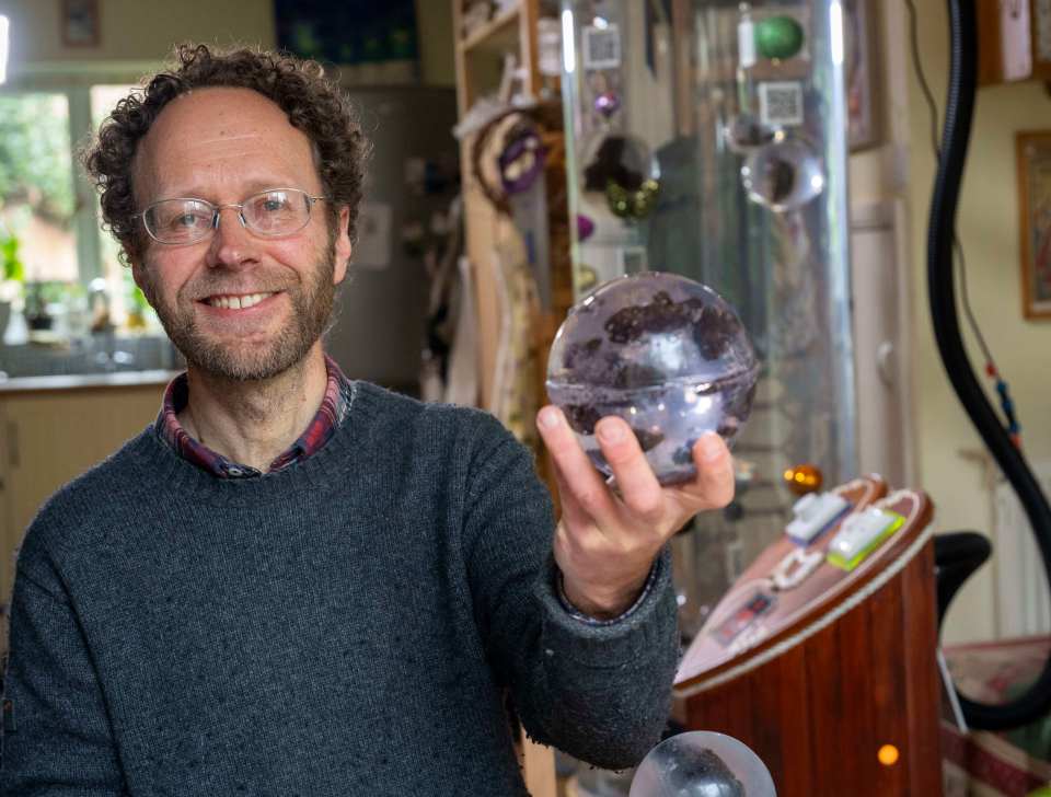 Man holding a glass sphere containing human feces.