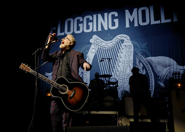 Dave King of Flogging Molly performing on stage with an acoustic guitar.