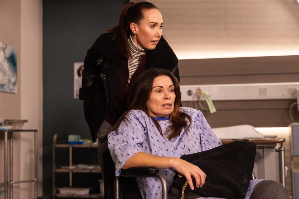 A woman in a hospital gown sits in a wheelchair while another woman stands behind her.