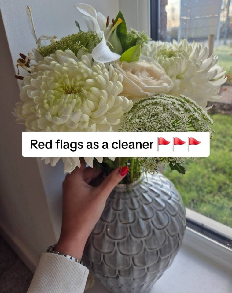 Hand arranging white flowers in a gray vase; text overlay: "Red flags as a cleaner" and three red flags.