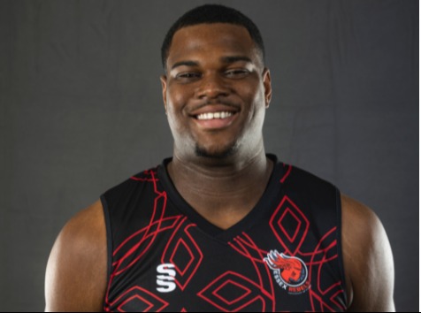 Headshot of a smiling man in a black jersey.