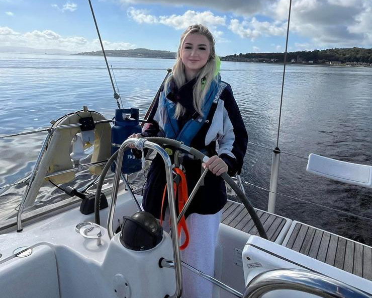 Young woman steering a sailboat.