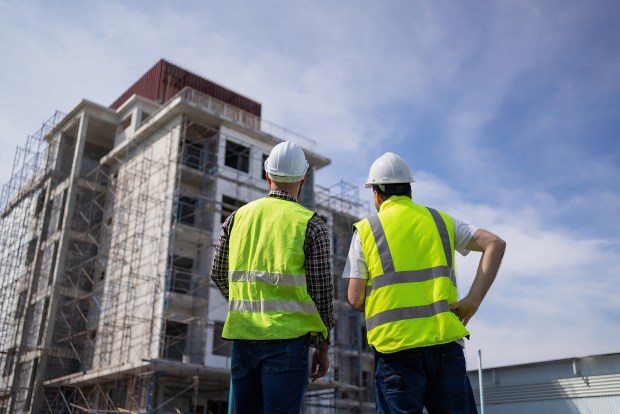 Two engineers reviewing building plans at a construction site.