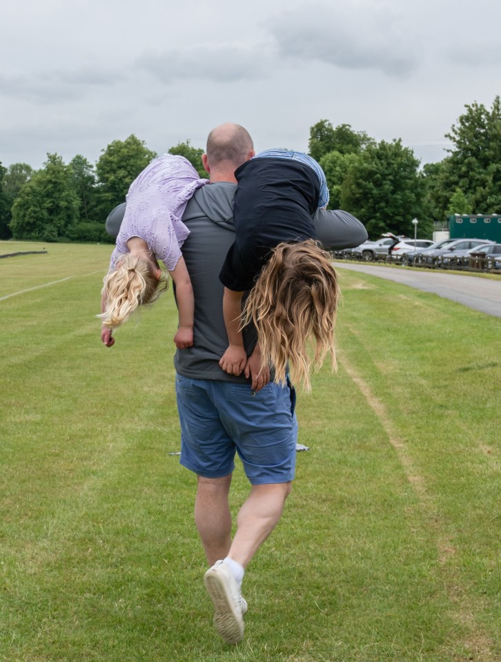 Man carrying two children on his shoulders at a polo match.