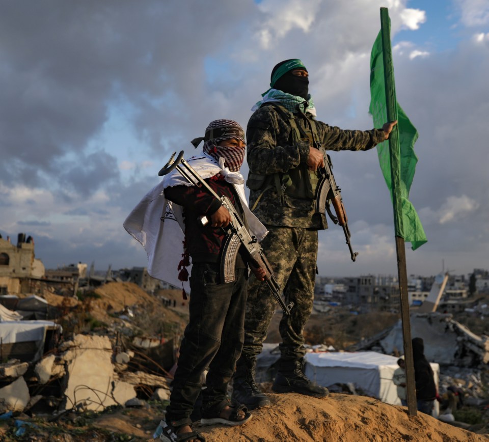 Boy with AK-47 rifle stands next to a Hamas fighter.