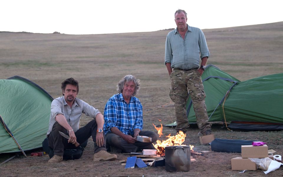 Three men camping by a campfire.