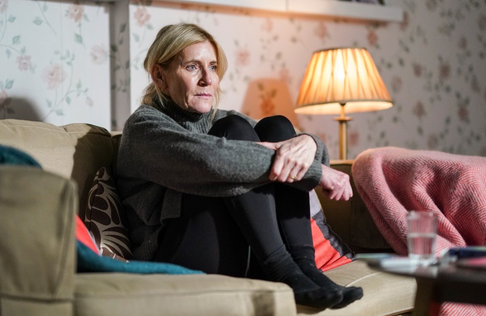 Michelle Collins as Cindy Beale sitting on a sofa.