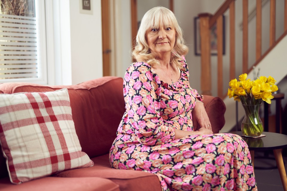 Woman in floral dress sitting on a sofa.