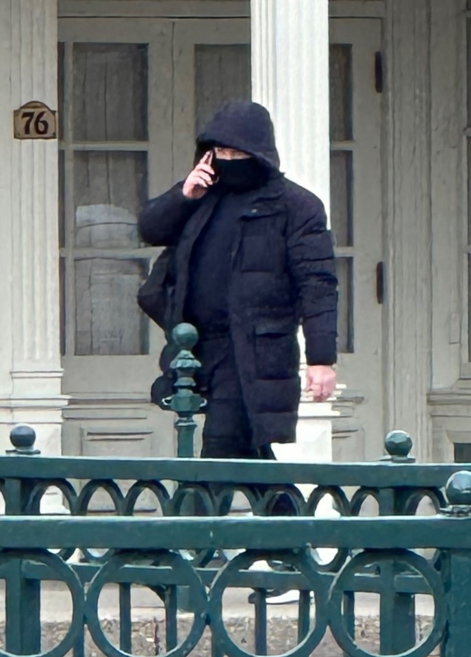 Wayne Rooney on a phone call, wearing a black hooded coat.