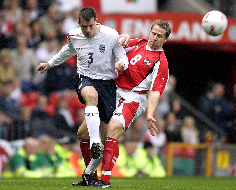 Jamie Carragher of England being tackled during a soccer match.