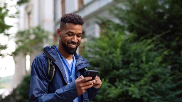 Smiling man using smartphone outdoors.