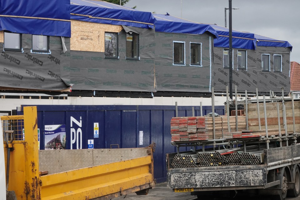 Construction site with building under construction and scaffolding materials on a truck.