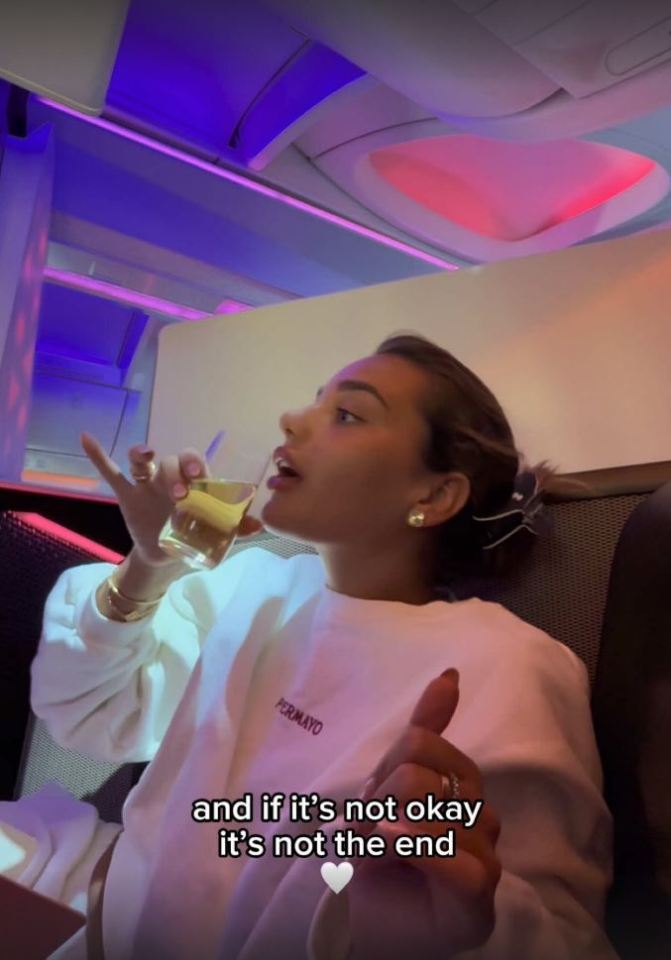 Woman on airplane drinking from a glass, caption reads, "and if it's not okay it's not the end."