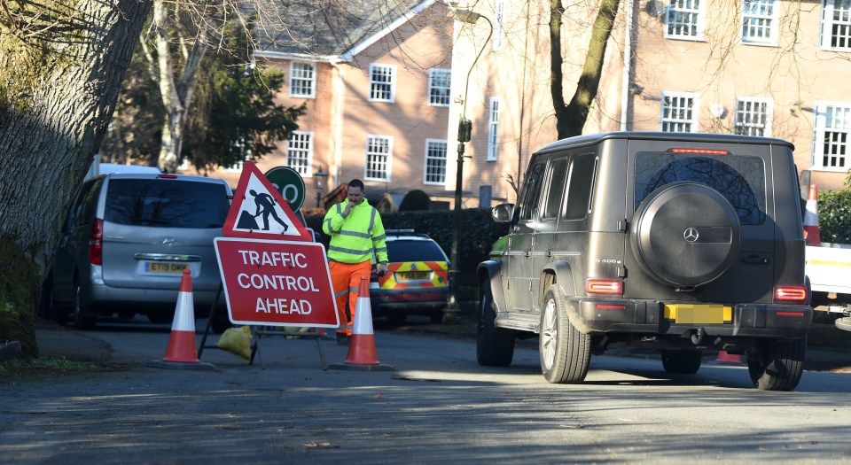 Traffic control ahead sign and worker near a Mercedes G-Class.