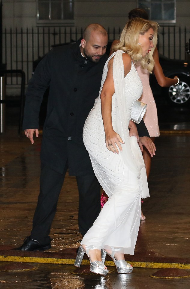 Woman in white dress almost falls while being assisted by a man.