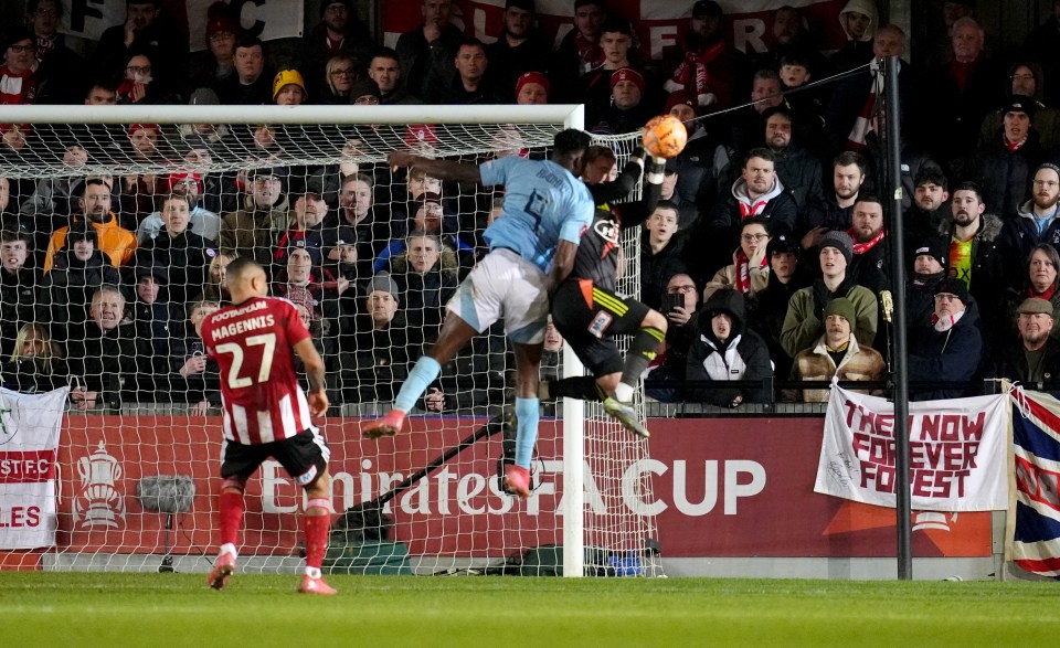 Soccer players battling for the ball in front of a goal.