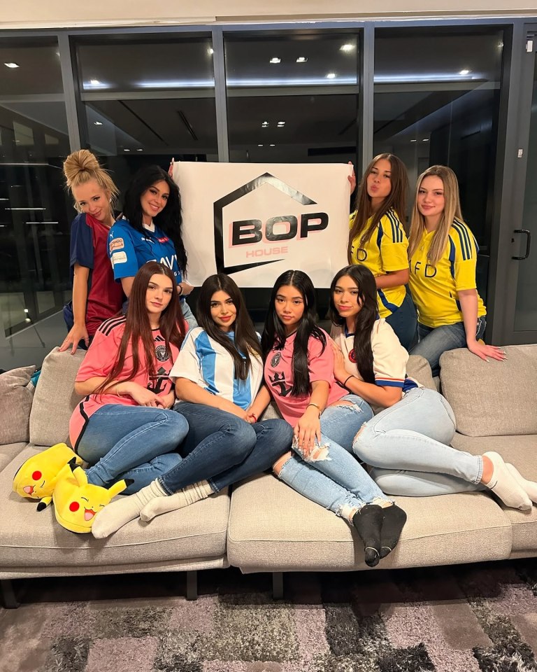 Eight women posing on a couch with a "Bop House" sign.