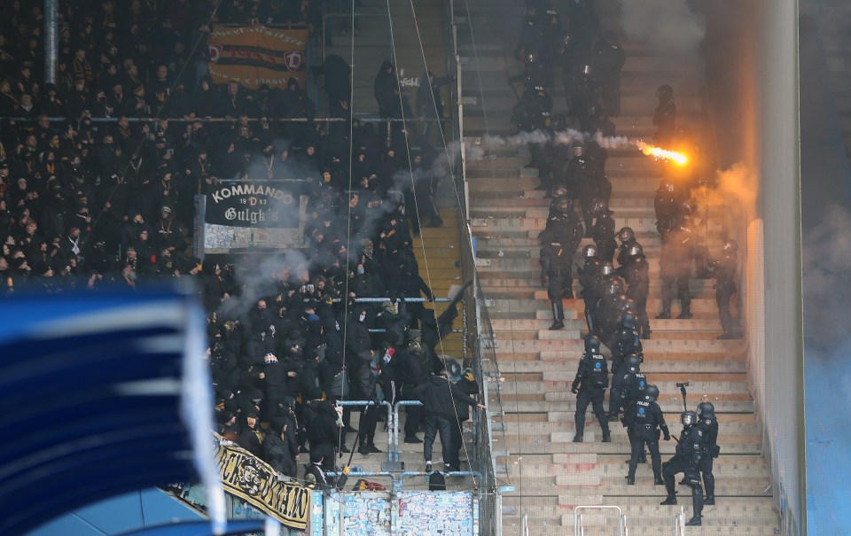 Soccer fans throwing flares at police in a stadium.