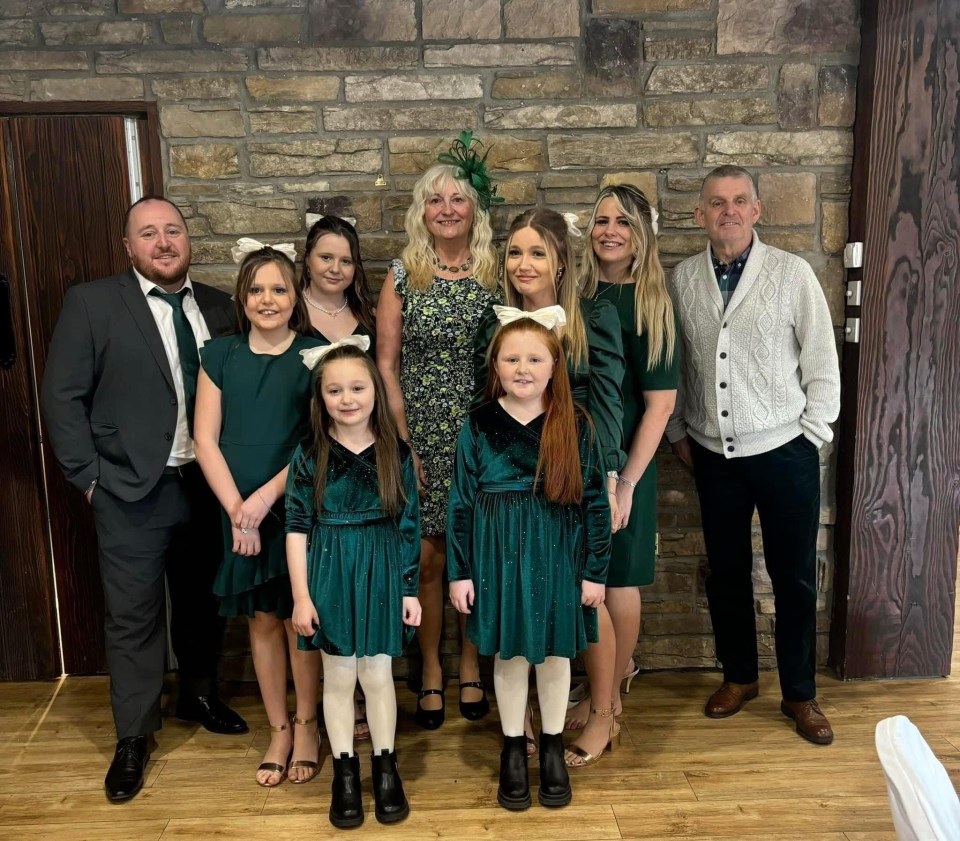 Group photo of two adults and seven children, all wearing green.