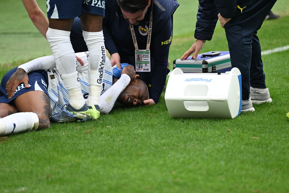 Fenerbahce's Talisca receiving medical attention on the field after an injury.