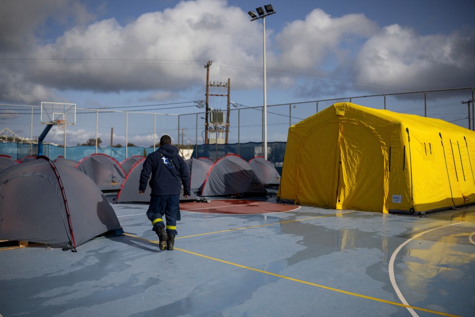 Firefighter walking past tents set up on a wet basketball court.